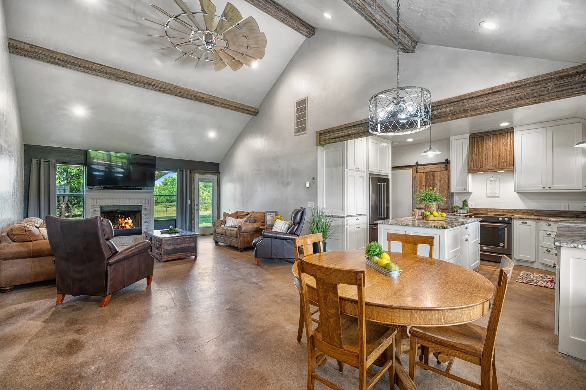 Vaulted great room with exposed beams opening onto the kitchen and dining table